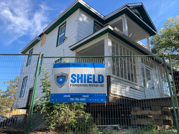 Image of a house surrounded by fencing and Shield signage