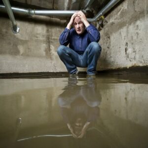 Photograph of a dismayed man in a flooded basement.