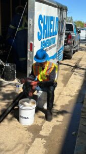 Image of Shield Foundation Repair employees spraying an application of WetSuit waterproofing product.