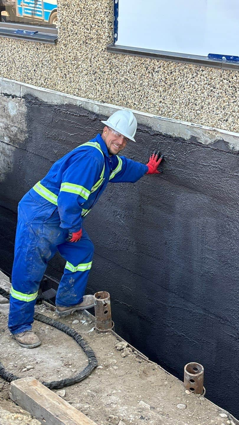 Image of Shield Foundation Repair employees spraying an application of WetSuit waterproofing product.