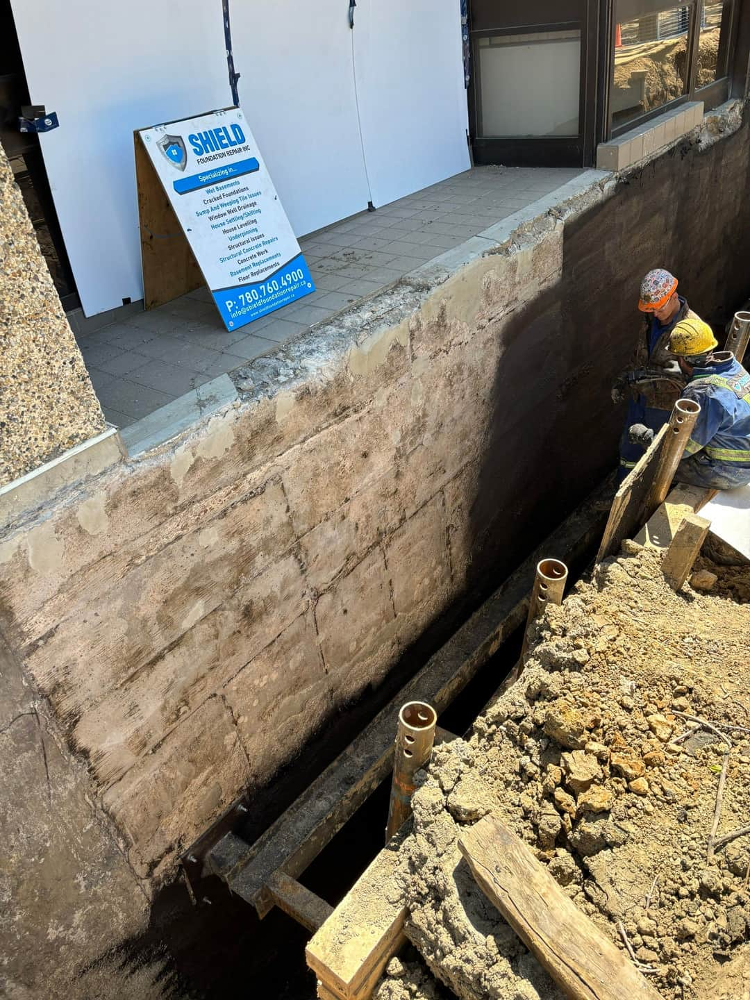 Image of Shield Foundation Repair employees spraying an application of WetSuit waterproofing product.